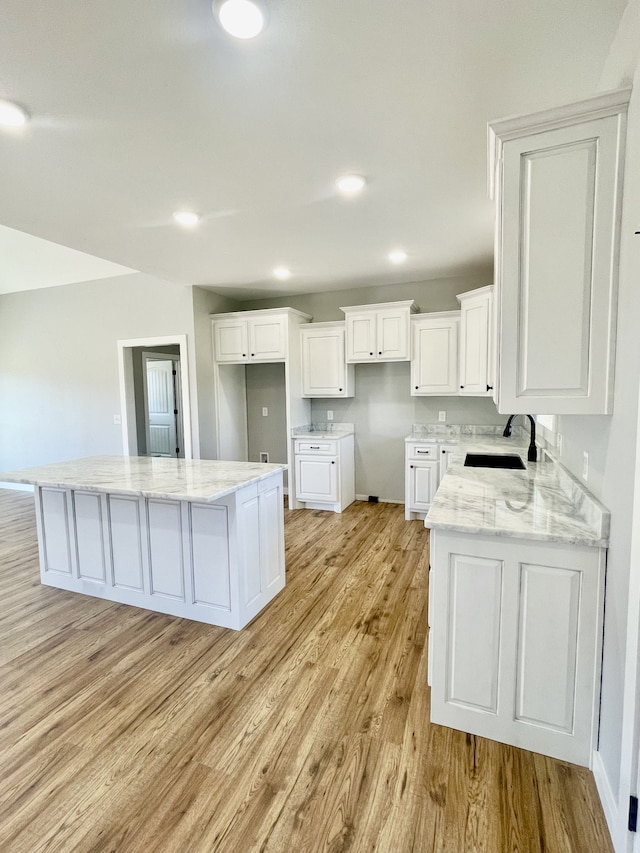 kitchen featuring light hardwood / wood-style floors, white cabinets, sink, and a kitchen island