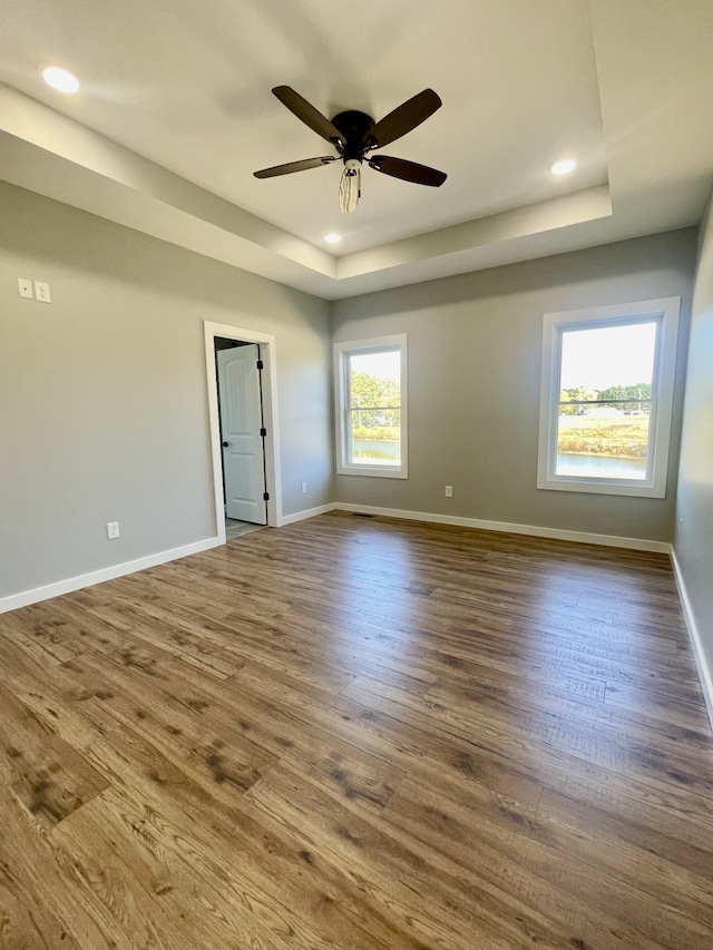 spare room with ceiling fan, wood-type flooring, and a tray ceiling