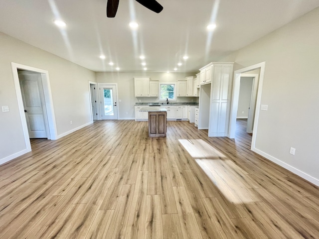 kitchen featuring white cabinets, a center island, light wood-type flooring, and ceiling fan