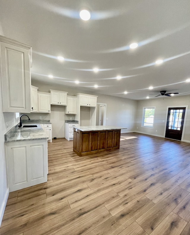 kitchen featuring white cabinets, sink, light wood-type flooring, and a kitchen island