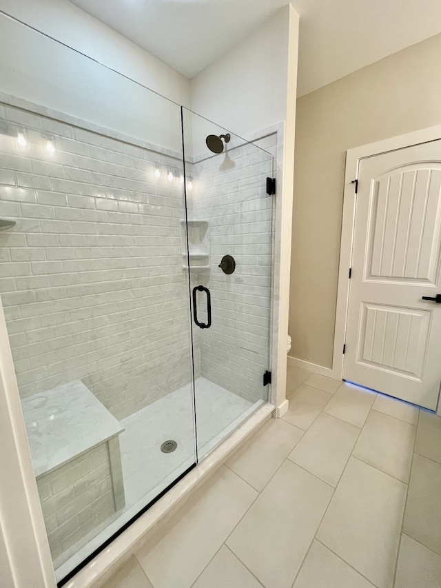 bathroom featuring a shower with shower door, toilet, and tile patterned flooring