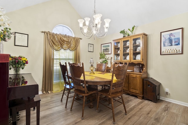 dining area featuring a chandelier, high vaulted ceiling, and light hardwood / wood-style flooring