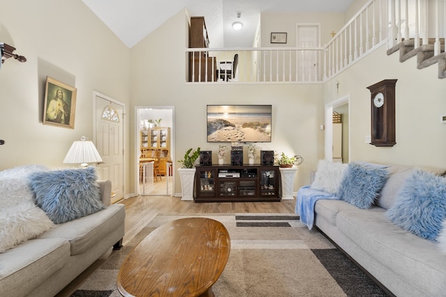 living room with high vaulted ceiling and light wood-type flooring