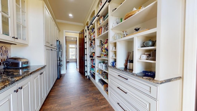 interior space featuring refrigerator, white cabinetry, dark stone countertops, crown molding, and dark wood-type flooring