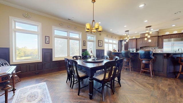 dining area with ornamental molding, a chandelier, and dark parquet flooring