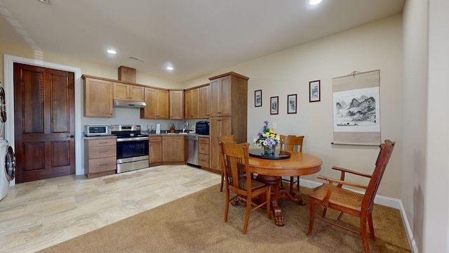 kitchen featuring light colored carpet, stacked washing maching and dryer, and stainless steel appliances