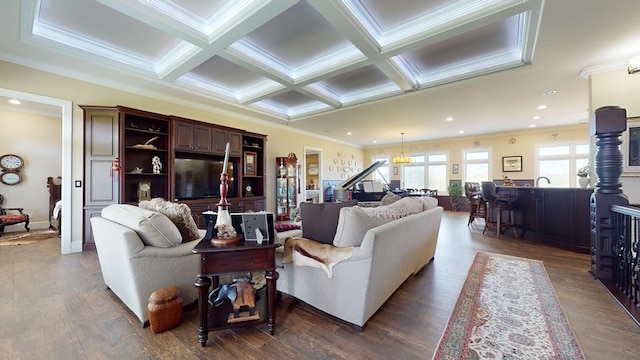 living room featuring coffered ceiling, beamed ceiling, ornamental molding, an inviting chandelier, and dark hardwood / wood-style flooring