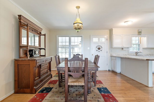 dining room with sink, light hardwood / wood-style flooring, and ornamental molding