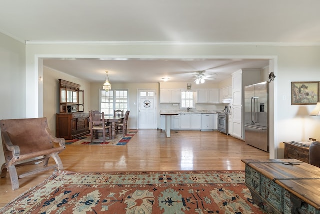 living room featuring sink, hardwood / wood-style flooring, a wealth of natural light, and ornamental molding