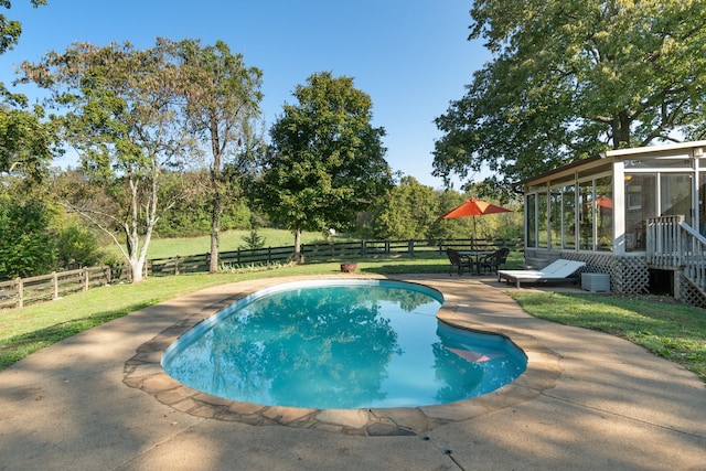 view of pool with a sunroom, a lawn, and a patio