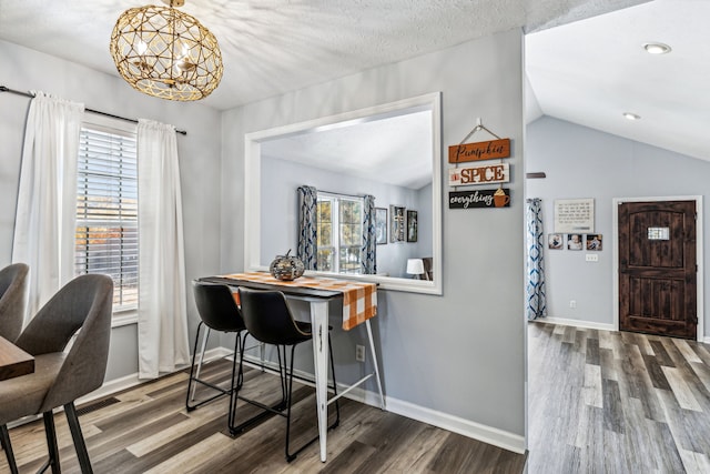 dining area featuring hardwood / wood-style floors, vaulted ceiling, and a notable chandelier