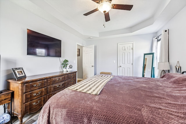 bedroom featuring hardwood / wood-style flooring, ceiling fan, and a raised ceiling