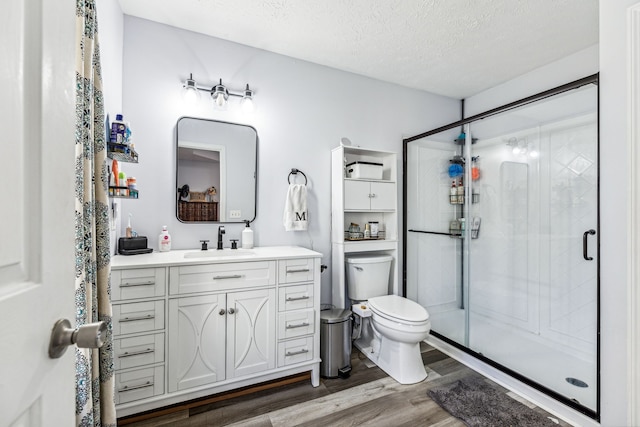 bathroom with a shower with door, vanity, wood-type flooring, and toilet