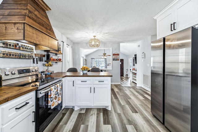 kitchen featuring appliances with stainless steel finishes, light hardwood / wood-style flooring, white cabinetry, and wood counters