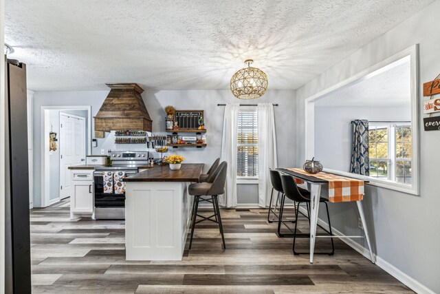 kitchen with a kitchen breakfast bar, white cabinetry, butcher block countertops, stainless steel electric range oven, and dark hardwood / wood-style flooring