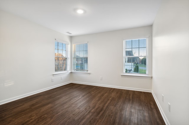 empty room with dark hardwood / wood-style flooring and a healthy amount of sunlight