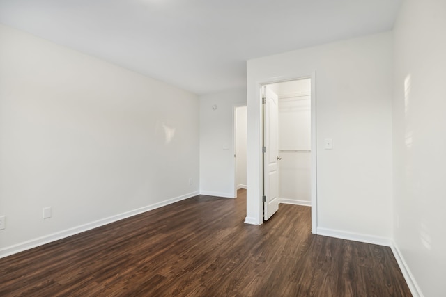 unfurnished bedroom with dark hardwood / wood-style floors, a spacious closet, and a closet