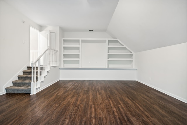 interior space with built in shelves, lofted ceiling, and dark hardwood / wood-style floors