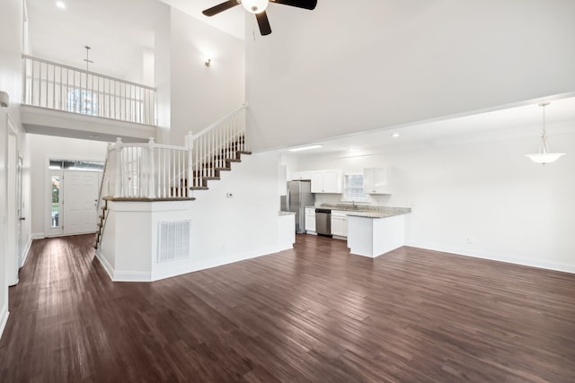 unfurnished living room with dark hardwood / wood-style flooring and a towering ceiling