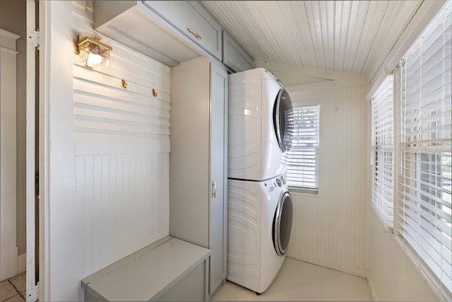 laundry area featuring stacked washer / dryer and wooden walls