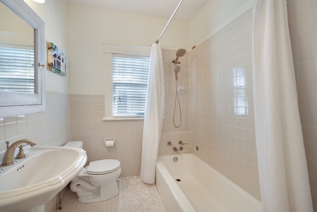 full bathroom featuring sink, shower / bath combination with curtain, toilet, tile patterned floors, and tile walls