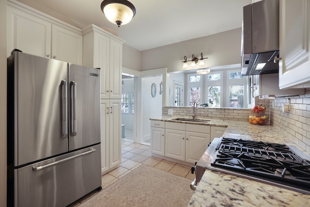 kitchen featuring appliances with stainless steel finishes, white cabinets, sink, and light stone counters