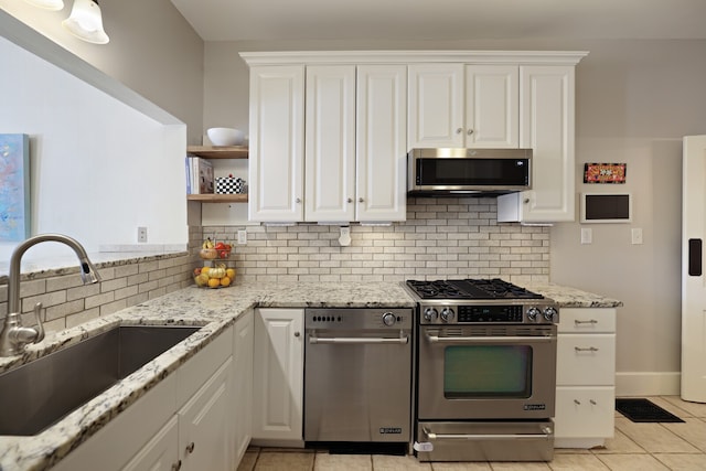 kitchen with decorative backsplash, stainless steel appliances, sink, light tile patterned flooring, and white cabinetry