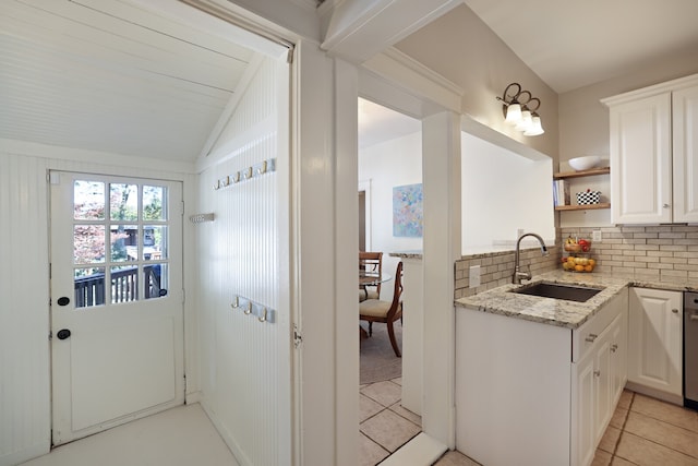 kitchen with white cabinets, tasteful backsplash, light stone counters, light tile patterned flooring, and sink