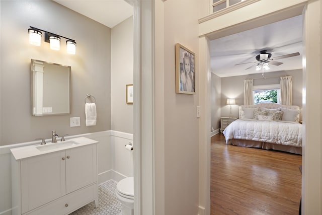 bathroom with toilet, hardwood / wood-style flooring, vanity, and ceiling fan