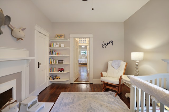 bedroom with dark hardwood / wood-style floors and a nursery area