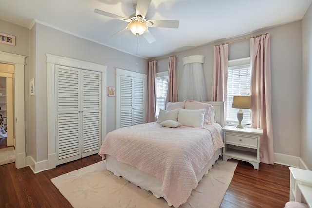 bedroom featuring multiple closets, dark hardwood / wood-style floors, and ceiling fan