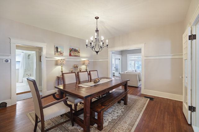 dining area with dark wood-type flooring and a notable chandelier