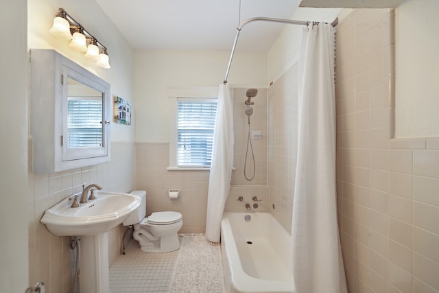 bathroom with tile walls, shower / tub combo with curtain, toilet, and tile patterned flooring