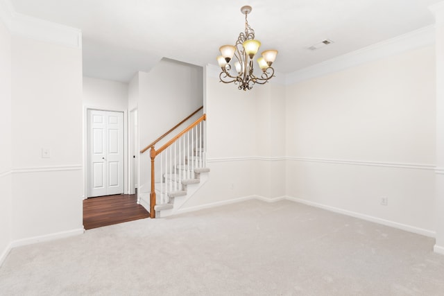 spare room with carpet floors, ornamental molding, and a notable chandelier