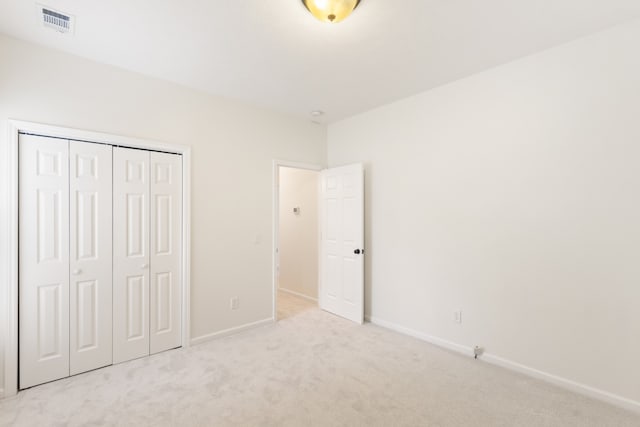 unfurnished bedroom featuring light carpet and a closet