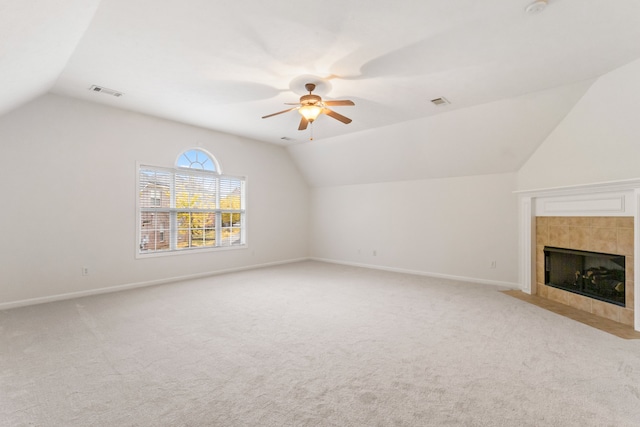 unfurnished living room featuring light carpet, vaulted ceiling, ceiling fan, and a tiled fireplace