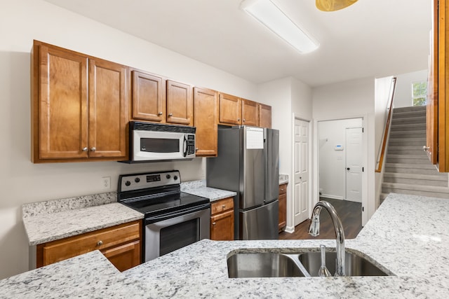 kitchen featuring light stone countertops, sink, stainless steel appliances, and hardwood / wood-style flooring