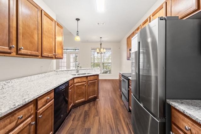 kitchen with appliances with stainless steel finishes, dark wood-type flooring, sink, a chandelier, and hanging light fixtures