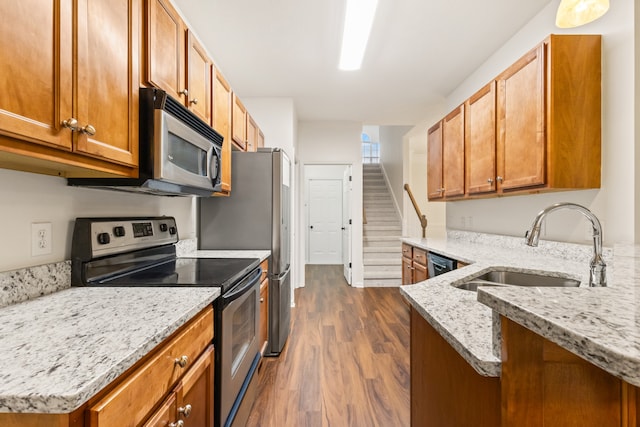 kitchen featuring sink, dark wood-type flooring, light stone counters, kitchen peninsula, and appliances with stainless steel finishes