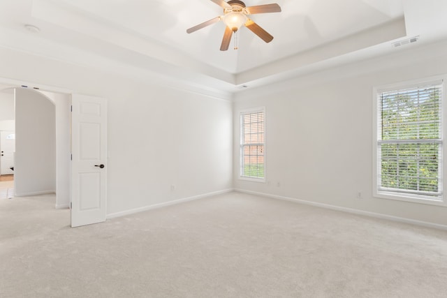 carpeted empty room featuring a tray ceiling and ceiling fan