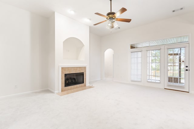 unfurnished living room with ceiling fan, light carpet, and a tiled fireplace