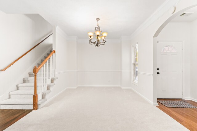 foyer entrance with a chandelier, ornamental molding, and hardwood / wood-style flooring