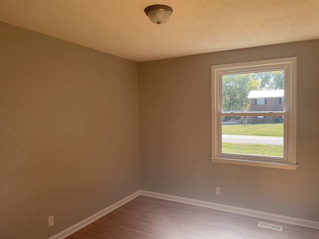 empty room with a textured ceiling and hardwood / wood-style flooring