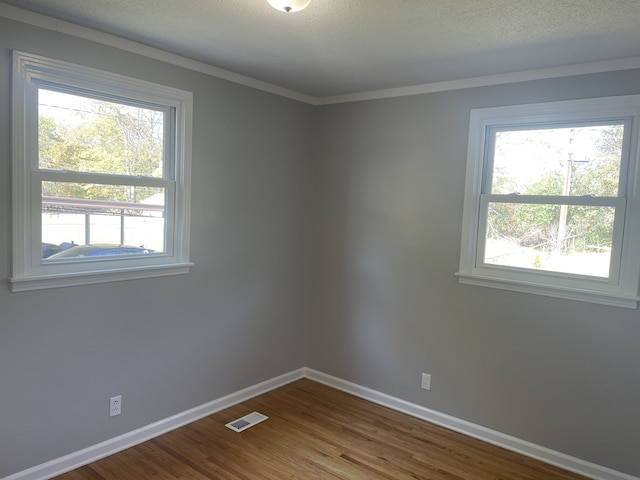 unfurnished room featuring hardwood / wood-style floors, crown molding, and a textured ceiling