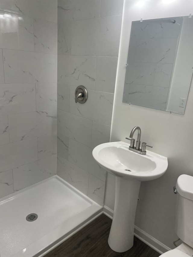 bathroom with toilet, hardwood / wood-style floors, and tiled shower