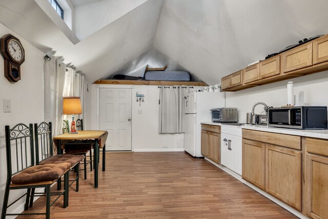 kitchen with vaulted ceiling, white refrigerator, and light hardwood / wood-style flooring