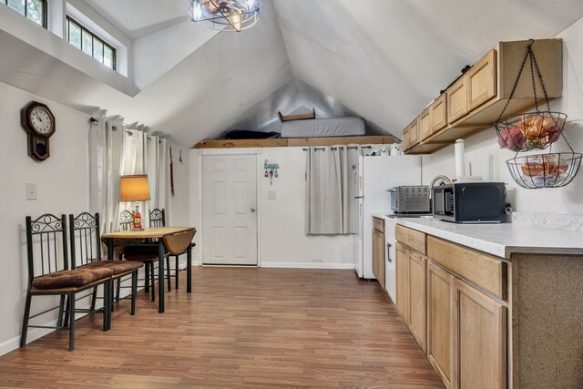 kitchen featuring light wood-type flooring, light brown cabinetry, and vaulted ceiling