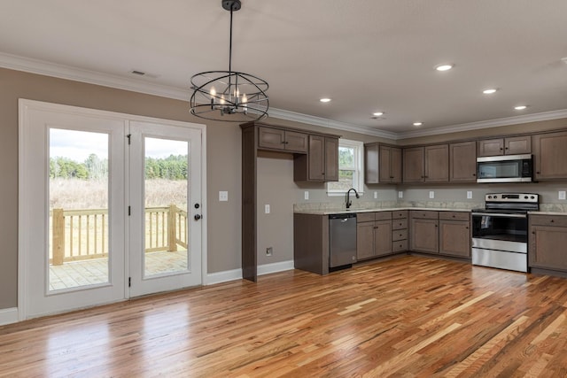 kitchen with appliances with stainless steel finishes, ornamental molding, pendant lighting, light hardwood / wood-style flooring, and an inviting chandelier