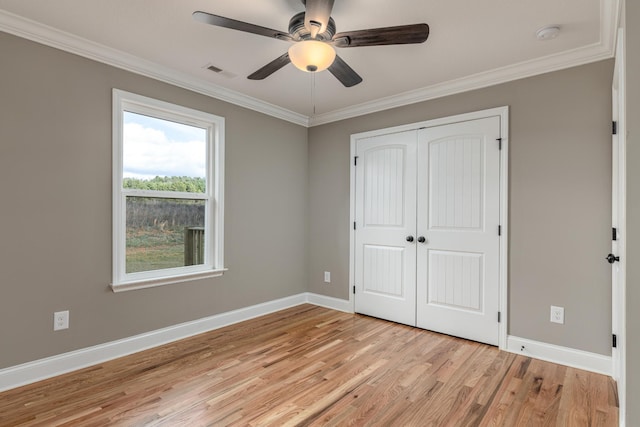 unfurnished bedroom with ceiling fan, light wood-type flooring, ornamental molding, and a closet