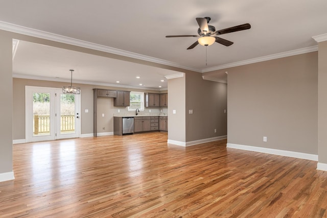 unfurnished living room featuring ceiling fan with notable chandelier, light hardwood / wood-style floors, sink, and crown molding